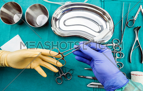 Surgeon working in operating room, hands with gloves holding scissors of suture and torondas, conceptual image, composicon horizontal
