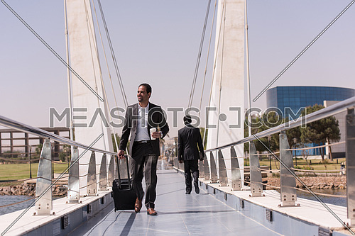 businessman walking with his suitcase at airport terminal and drink fresh morning coffee