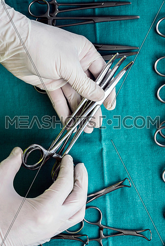 Surgeon working in operating room, hands with gloves holding scissors, conceptual image, vertical composition