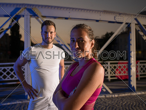 urban sports, portrait of a healthy couple jogging across the bridge in the city at early morning in night