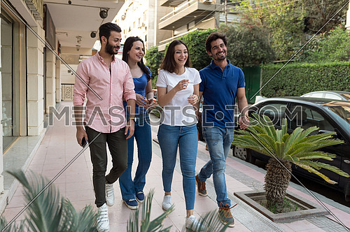 A group of young people speak and laugh as they walk in the street