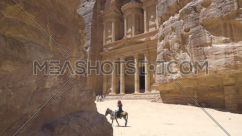 Pan down to Jordanian man riding a donkey in Petra
