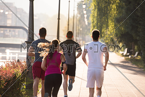 group of young sporty people jogging at sunny morning in the city