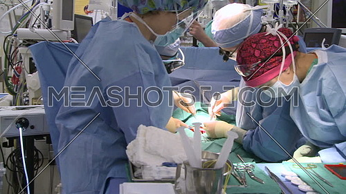 Pan Right long shot of operating room while medical team performing surgery