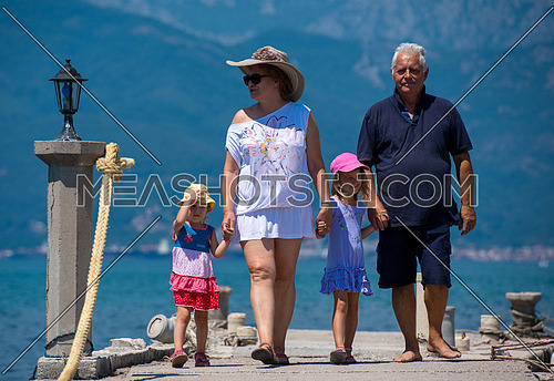 happy grandparents with cute little granddaughters having fun holding their hands while walking  by the sea during Summer vacation  Healthy family holiday concept