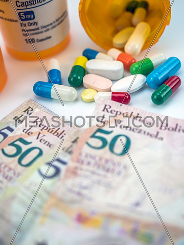 Medicines next to banknotes of Venezuela, shady deal of medication in full crisis of country of Latin America, conceptual image, composition vertical