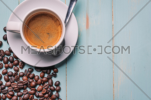White cup of coffee,teaspoon and coffee bean on water blue background. Copy space,view from above.