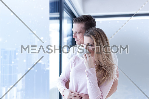 romantic happy young couple enjoying morning coffee by the window on cold winter day at home