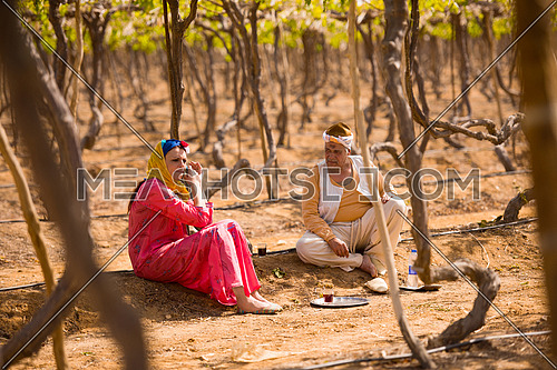 older middle eastern farmer and a young girl enjoyed sitting on the farm grapes