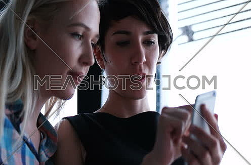 two business woman using cell phone in modern office bulding