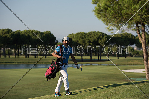 handsome middle eastern golfer carrying  bag  and walking to next hole at golf  course