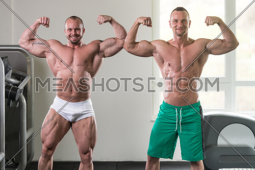 Two Guys Standing Strong In The Gym And Flexing Muscles - Muscular Athletic Bodybuilder Fitness Model Posing After Exercises