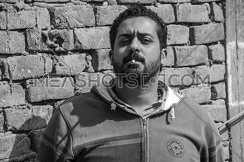 Medium Shot for Young man with beard smoking a cigarette monochrome 