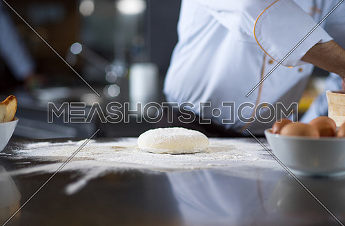 chef hands preparing dough for pizza on table sprinkled with flour closeup