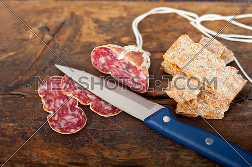 slicing italian salame pressato pressed over old wood table