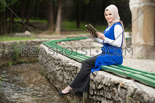 Young Muslim Woman Is Reading The Koran Outdoors