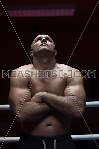 portrait of muscular professional kickboxer with arms crossed in the ring