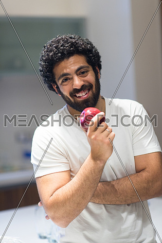 young middle east man with apple in the kitchen with satisfaction