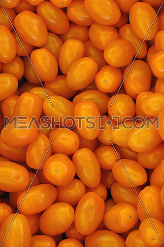Close up fresh yellow cherry tomatoes at retail display of farmers market, high angle view