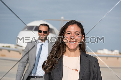 young successful middle eastern business woman walking with their business partners in front of private airplane