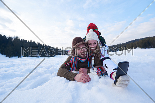 happy  romantic couple have fun in fresh snow and taking selfie. Romantic winter scene in forest with young people