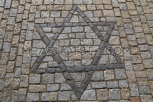 Close up background with Star of David, Magen David, Jewish religious and cultural heritage symbol on cobblestone paved road, high angle view