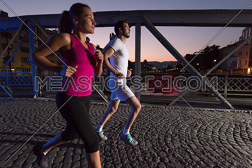 urban sports, healthy couple jogging across the bridge in the city at early morning in night