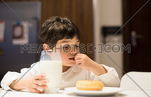 little middle east boy in the kitchen eating a snack and drinks milk with pleasurelittle middle east boy and girl eating snacks and drinking milk in the kitchen with pleasure