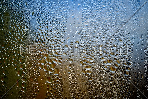 Condensation with beaded moisture droplets on the outside of a cold glass or bottle in a close up full frame background texture