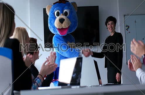 Boss dressed as teddy bear having fun with bussines people in modern corporate office