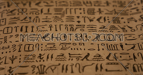 Close up background of ancient Egyptian hieroglyphs written on brown parchment paper, low angle view, selective focus