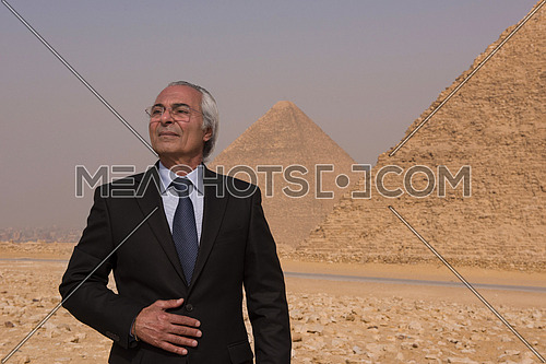 portrait of mature middle eastern business man in front of ancient egyptian pyramids