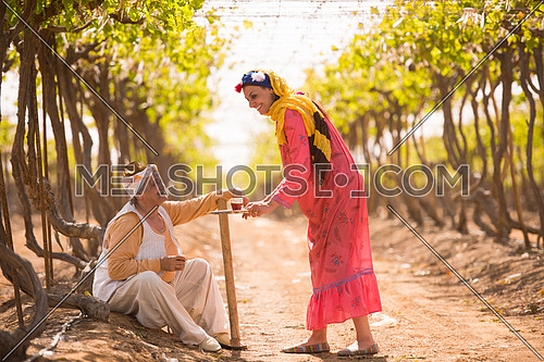 older middle eastern farmer and a young girl enjoyed sitting on the farm grapes