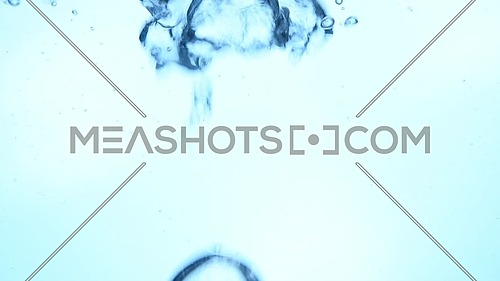 Extreme close up abstract background of air bubbles emerging underwater over white background in blue light, low angle side view, slow motion