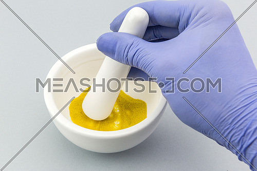 Pharmacist preparing formula master for cosmetic in white mortar on a white background