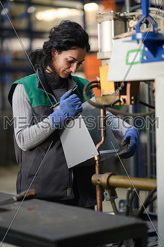 a woman working in a modern metal factory assembles parts for a new machine. High quality photo