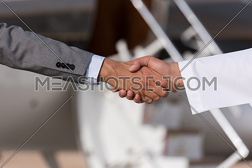 Young successful businessman shake hands with their Arab business partner in front of the private airplane