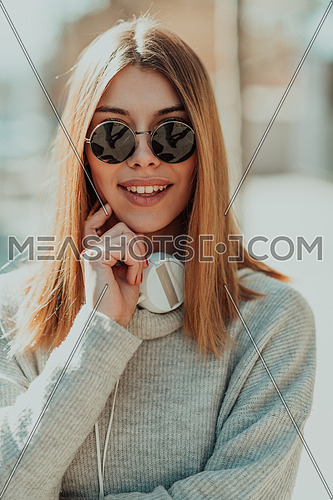 a woman in sunglasses enjoys a walk in the city while listening to music on her headphones