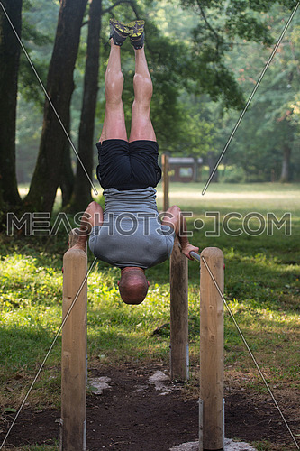 Athlete Working Out Hand Stand On Parallel Bars In An Outdoor Gym - Doing Street Workout Exercises