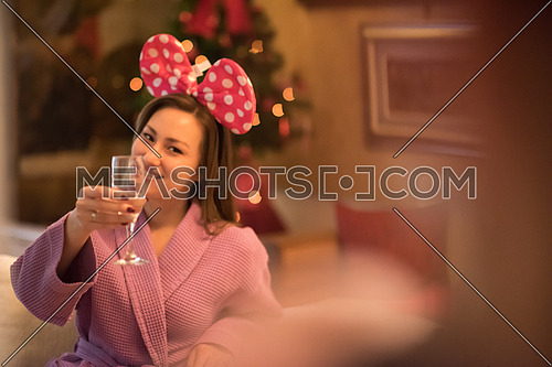 people, and relaxation concept   beautiful young woman in bath robe drinking champagne at spa over holidays lights background