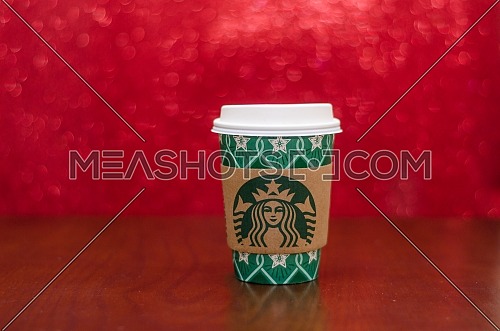 Starbucks takeaway paper cup, in special design for Christmas on a festive red background; December 2018 - Cairo, Egypt.