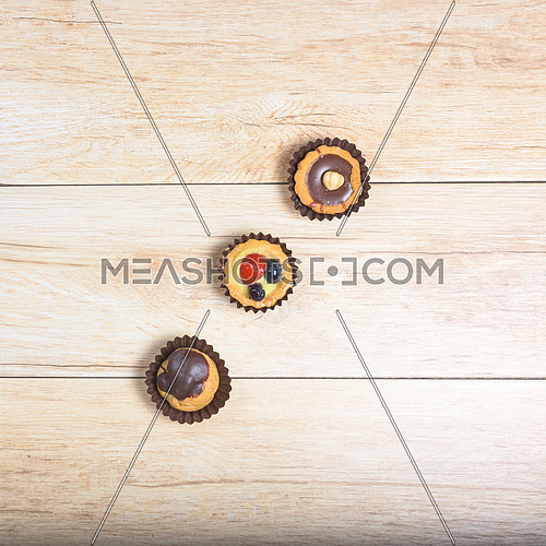 Pictured pastries on light wood background,above view,square photo.