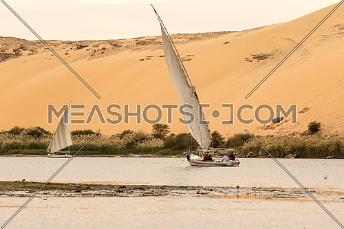 Ferry boat in River Nile, Aswan, Egypt. And sand hill in the background and some bushes