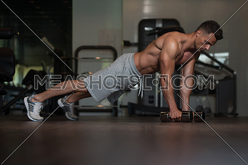 Young Man Athlete Doing Pushups With Dumbbells As Part Of Bodybuilding Training