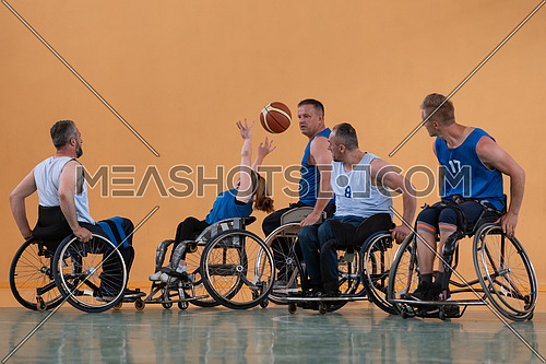 Disabled War veterans mixed race opposing basketball teams in wheelchairs photographed in action while playing an important match in a modern hall. High quality photo