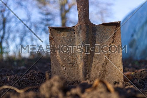rusty spade stuck to the ground against a background of blue sky and spring fields. Spring work start concept