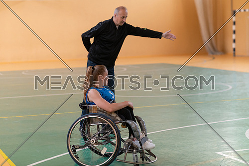 a sports basketball coach explains to a disabled woman in a wheelchair which position to play during a game. High quality photo