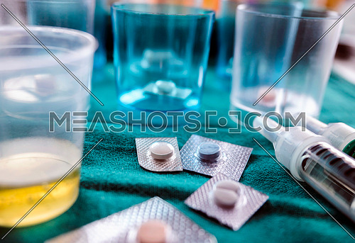 Diverse medication in glasses monodose along with insulin injectors in hospital, conceptual image, horizontal composition