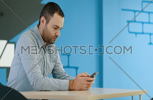 relaxed young businessman using smart phone at modern startup business office