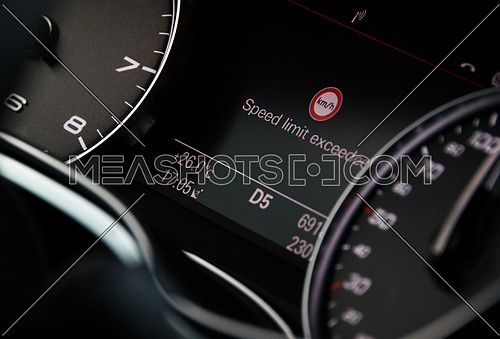 A car dashboard showing exceeding speed limit warning